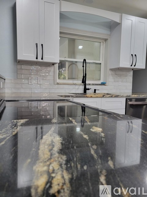 A kitchen with a marble counter top and white cabinets.