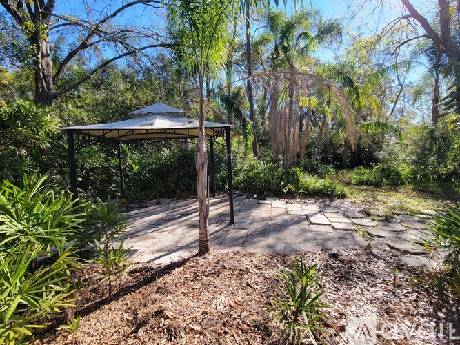 A gazebo is situated in a garden with a gravel path.
