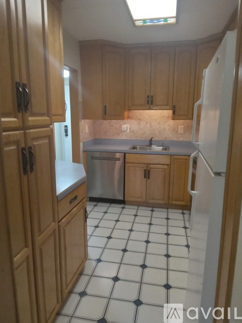 A kitchen with wooden cabinets and a black and white tiled floor.