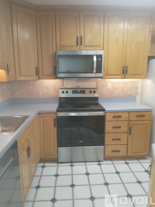 A kitchen with wooden cabinets and a black and white tiled floor.