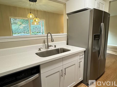 A modern kitchen with a stainless steel refrigerator and a double sink.