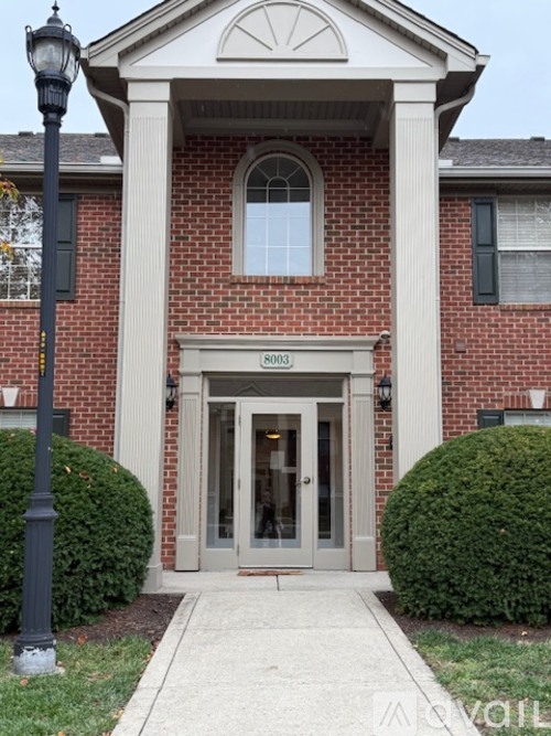 The front of a building with a brick facade and a large arched window above the door.