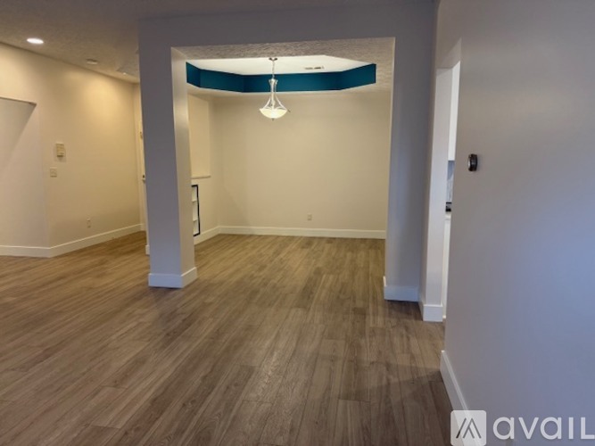 A room with wooden flooring and a white column.