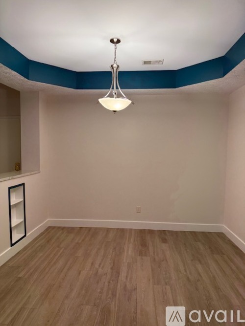 A room with a wooden floor and a chandelier hanging from the ceiling.