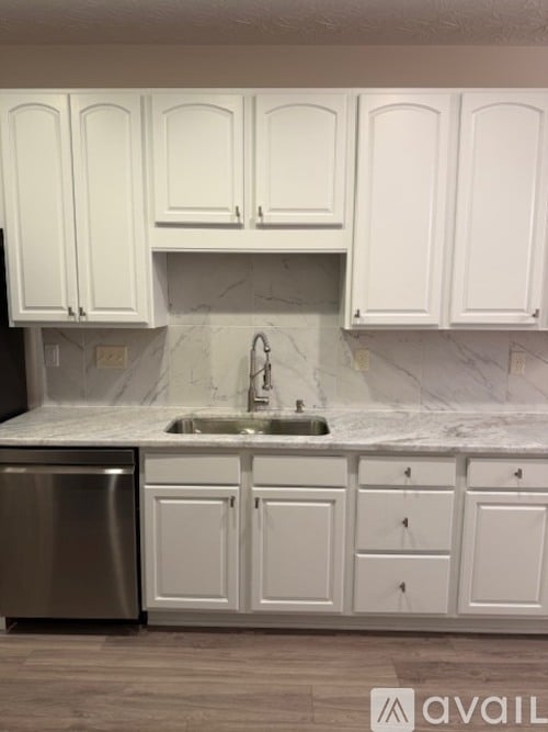 A kitchen with white cabinets and a marble backsplash.