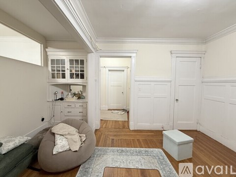 A room with a grey bean bag chair and a white cabinet with glass doors.