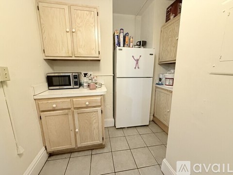 A kitchen with a white refrigerator, wooden cabinets, and a microwave.