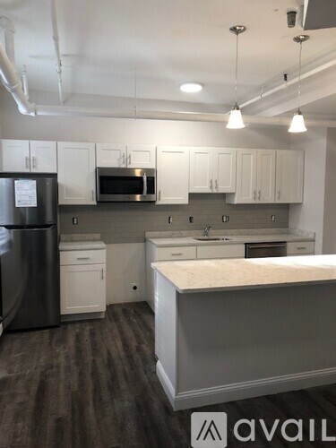 A kitchen with white cabinets and a black fridge.