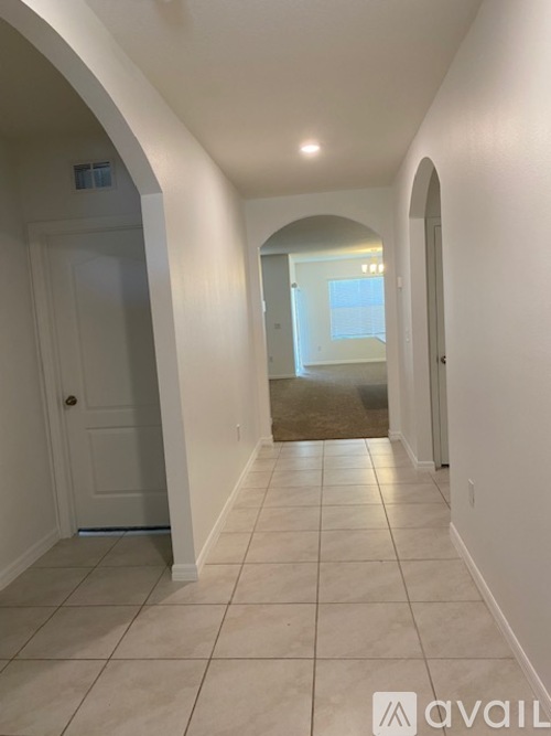 A hallway with white walls and a tiled floor.