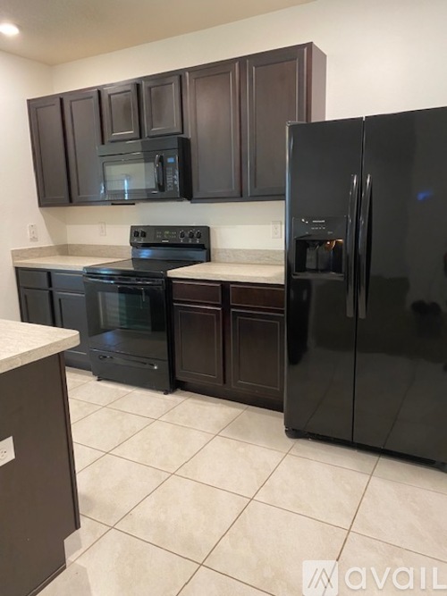 A kitchen with black appliances and brown cabinets.