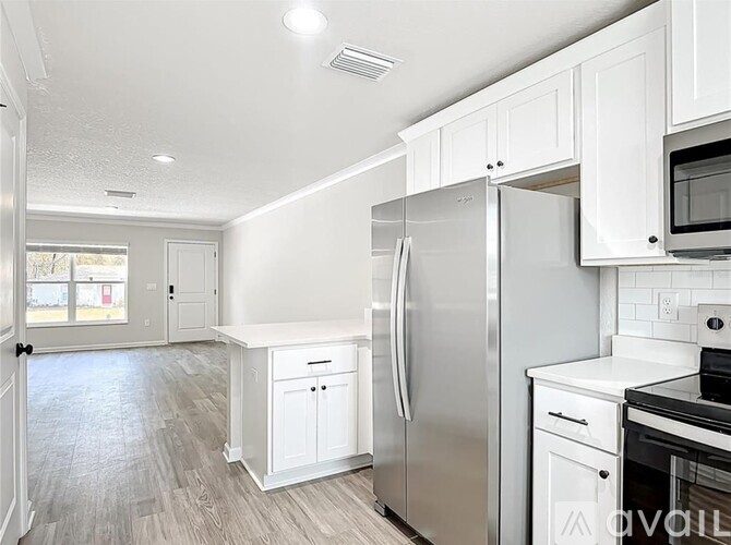 A white kitchen with a refrigerator, microwave, and oven.