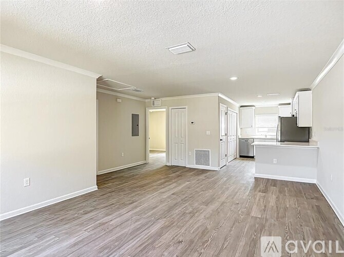 A spacious living room with wood flooring and a flat-screen TV.