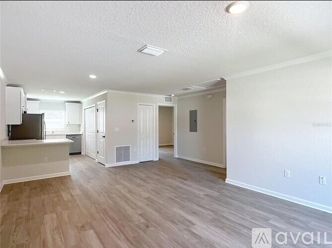 A spacious living room with wood flooring and white walls.