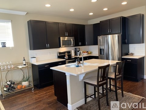 A kitchen with black cabinets and a white island.