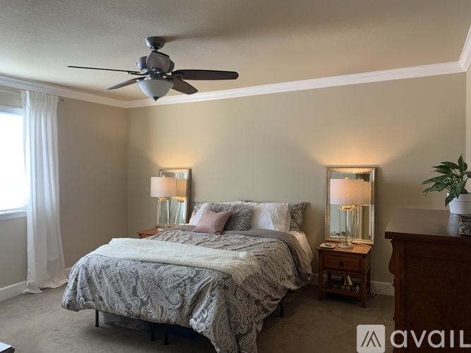 A bedroom with a bed, two lamps, and a ceiling fan.