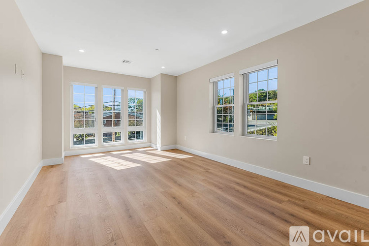 A spacious room with wooden floors and large windows.