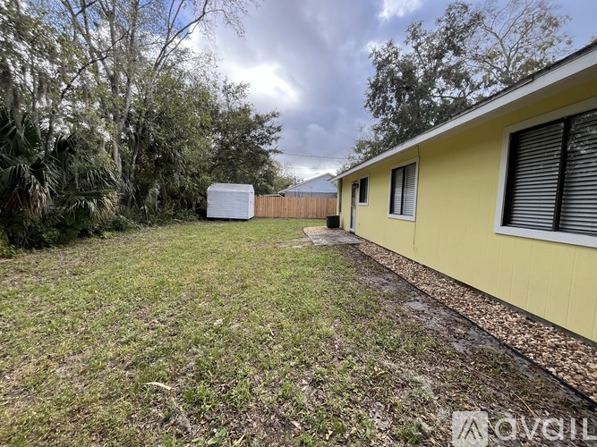 A yellow house with a white shed in the backyard.