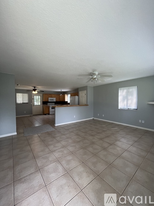 A spacious living room with tile flooring and a ceiling fan.