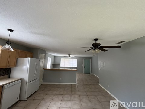 A kitchen with a refrigerator, ceiling fan, and tiled floor.