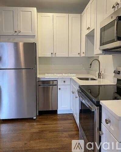 A kitchen with white cabinets and a stainless steel refrigerator.