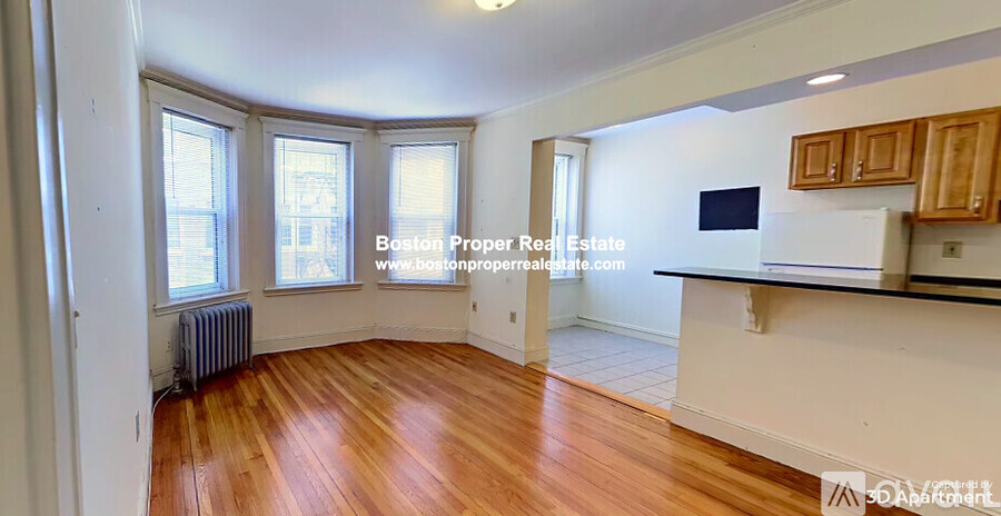A room with wooden floors and white walls, with a window and a radiator.