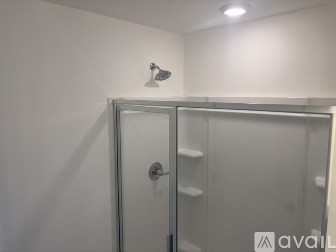 A shower with a glass door is in a white bathroom.