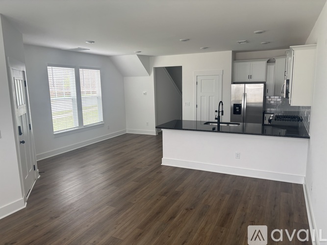 A spacious kitchen with dark wood floors and white walls.