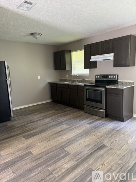 A kitchen with a black fridge, stove, and cabinets.