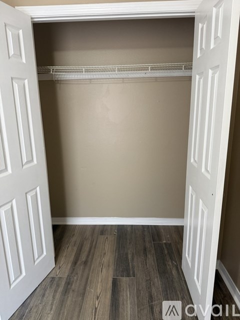 A white closet with a white door and a white shelf.