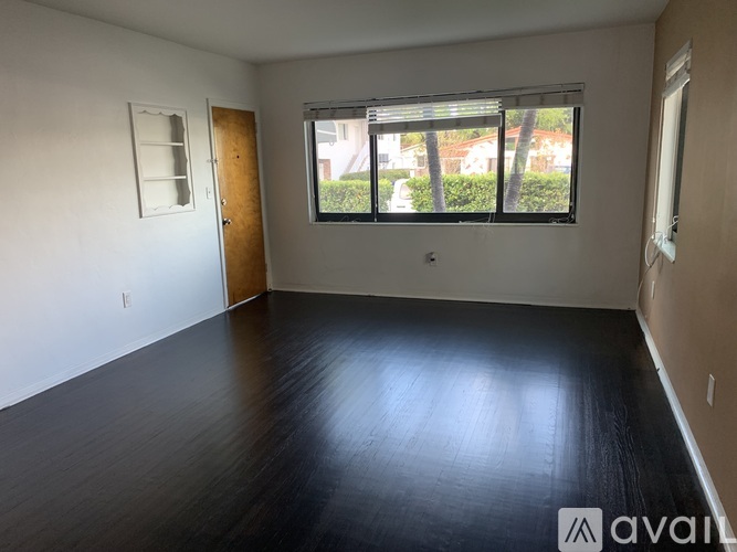 A room with wooden floors and a window with blinds.