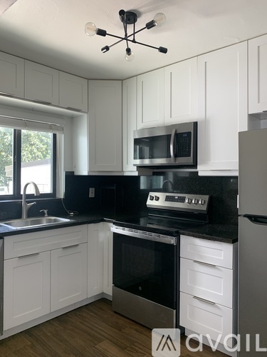 A kitchen with white cabinets and black countertops.