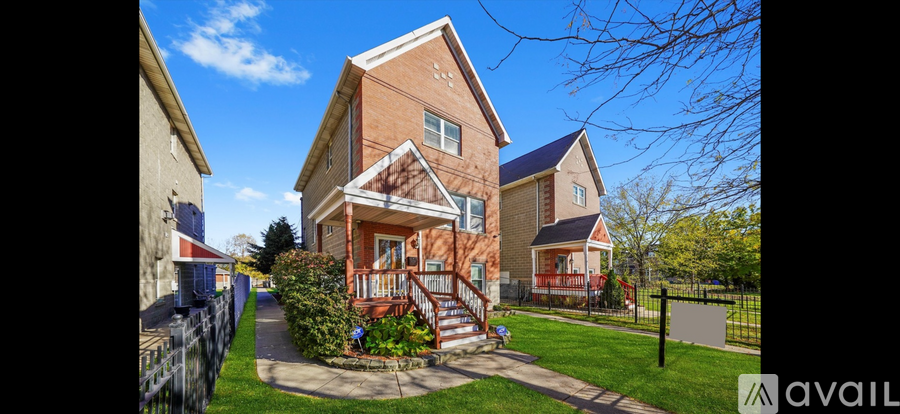 A two-story house with a red front porch and a black fence.