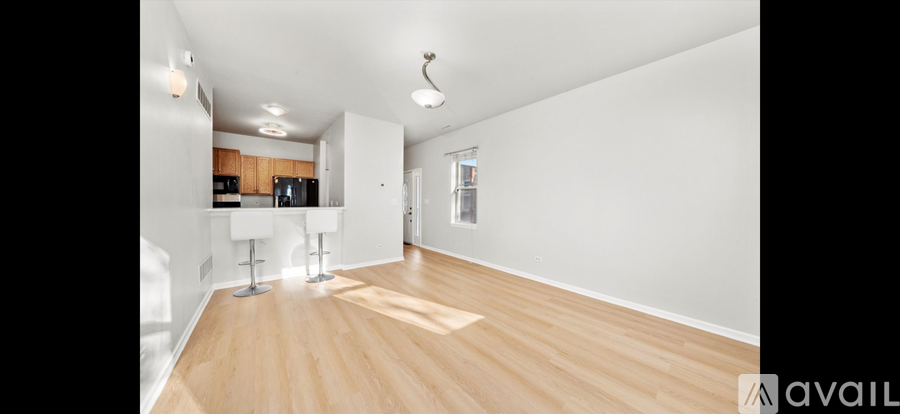 A spacious room with wooden flooring and white walls.