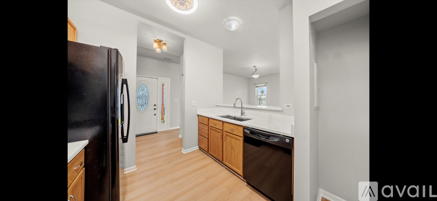 A kitchen with wooden cabinets and a black refrigerator.