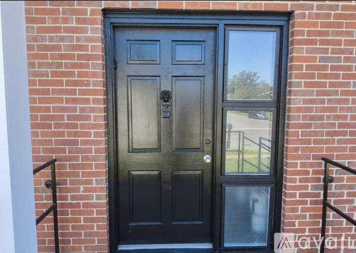 A black door with a glass window is set in a brick wall.