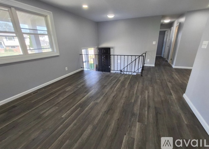 A room with wooden flooring and a black railing.