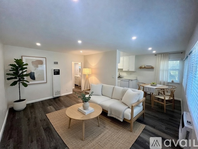 A living room with a white sofa, wooden coffee table, and a plant.