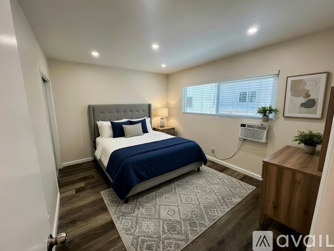 A bedroom with a bed, nightstand, and window.