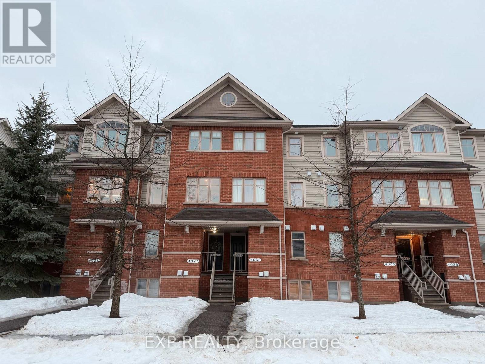 A large brick building with multiple windows and doors, surrounded by snow.