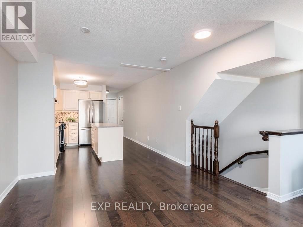 A well-lit, spacious room with wooden floors and a staircase with a wooden railing.