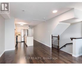 A well-lit, spacious room with wooden floors and a staircase with a wooden railing.