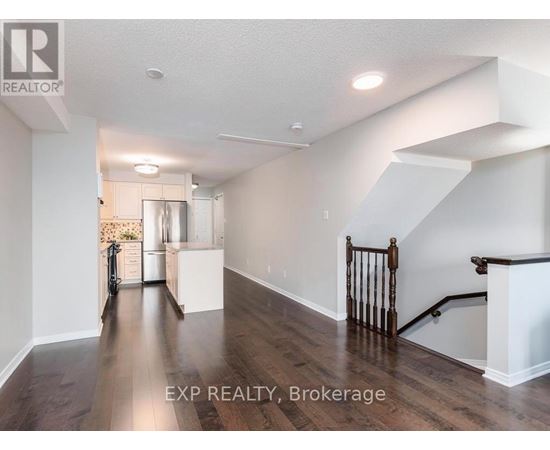 A well-lit, spacious room with wooden floors and a staircase with a wooden railing.