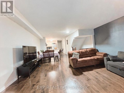 A living room with a brown couch and a wooden floor.