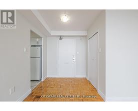 A white hallway with a wooden floor and a door on the right.