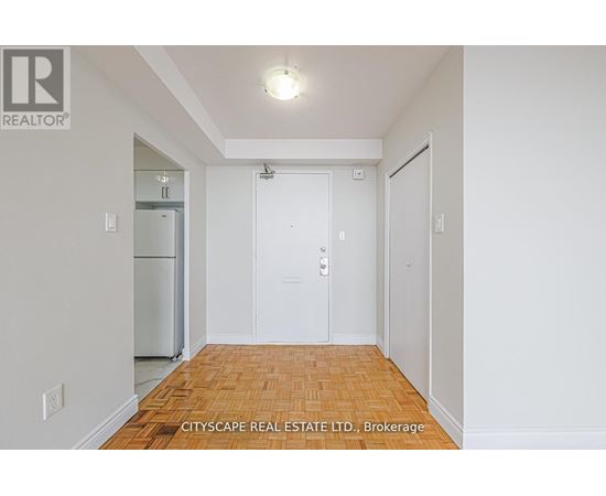 A white hallway with a wooden floor and a door on the right.