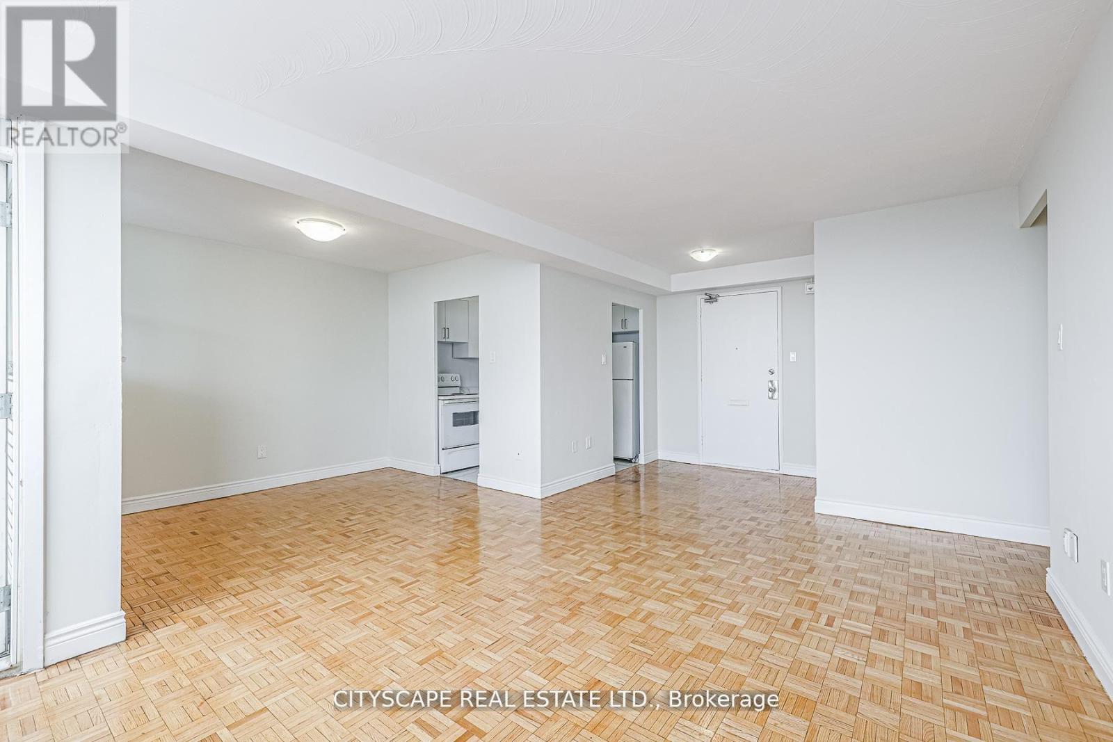 A spacious room with wooden flooring and white walls.