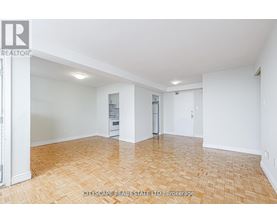A spacious room with wooden flooring and white walls.