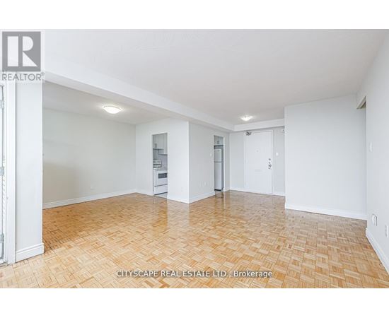 A spacious room with wooden flooring and white walls.