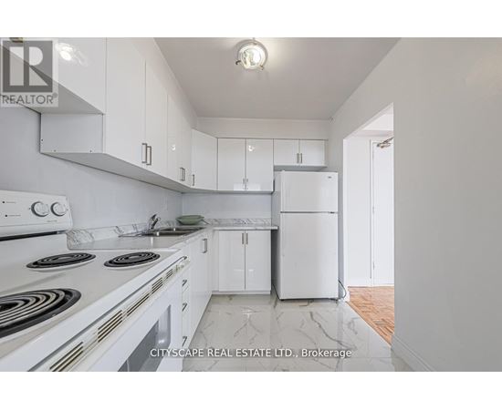 A white kitchen with a stove top oven and a refrigerator.