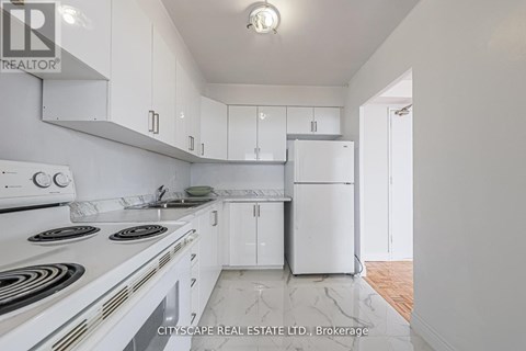 A white kitchen with a stove top oven and a refrigerator.